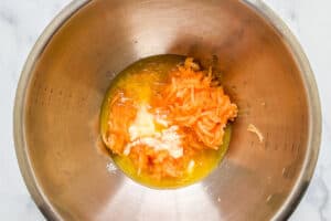 Melted butter and grated cantaloupe in a mixing bowl.