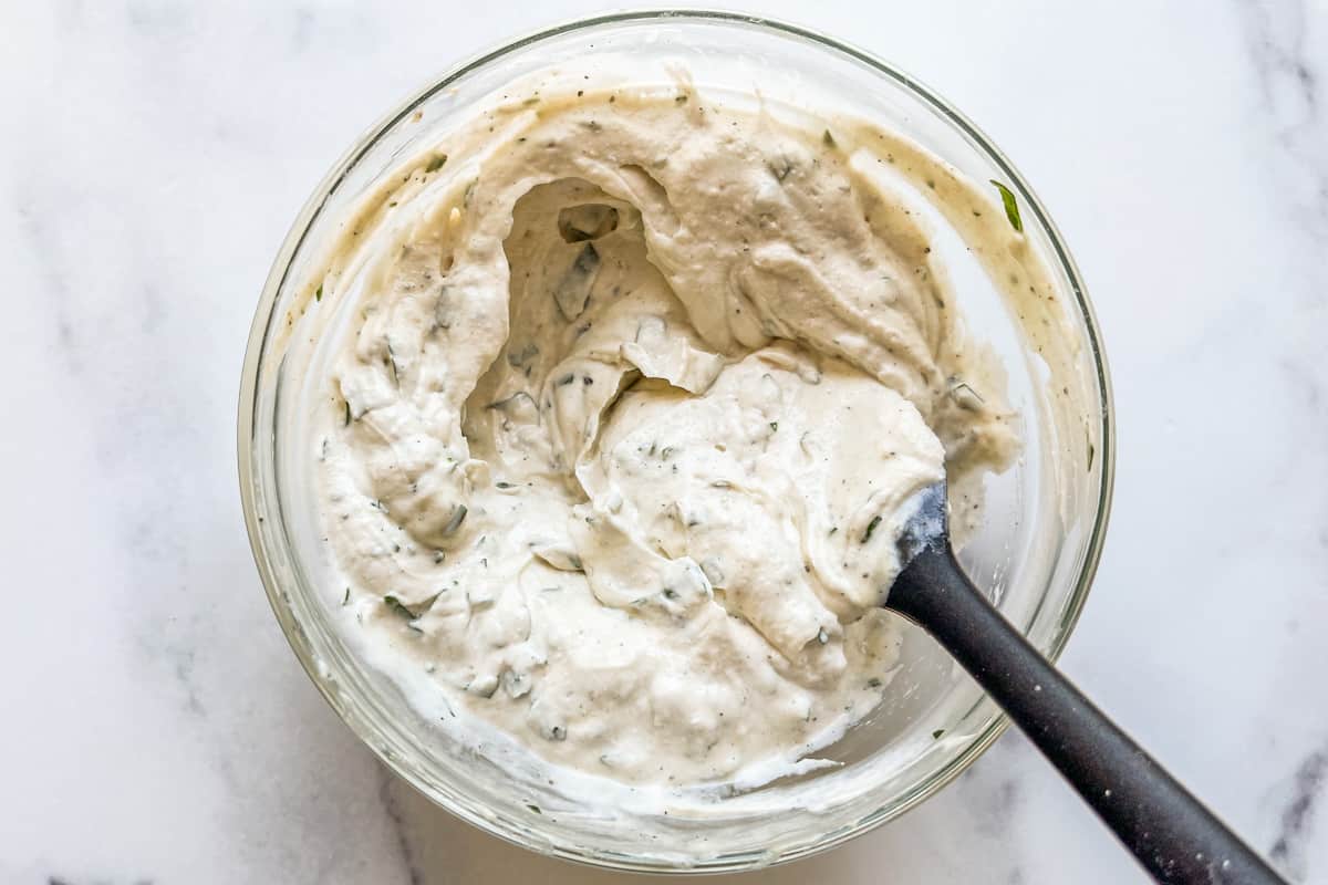 A bowl of tahini yogurt sauce being mixed.