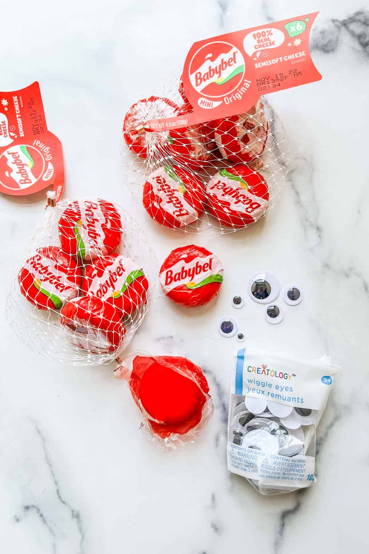 Two bags of babybel cheese and a packet of googly eyes.