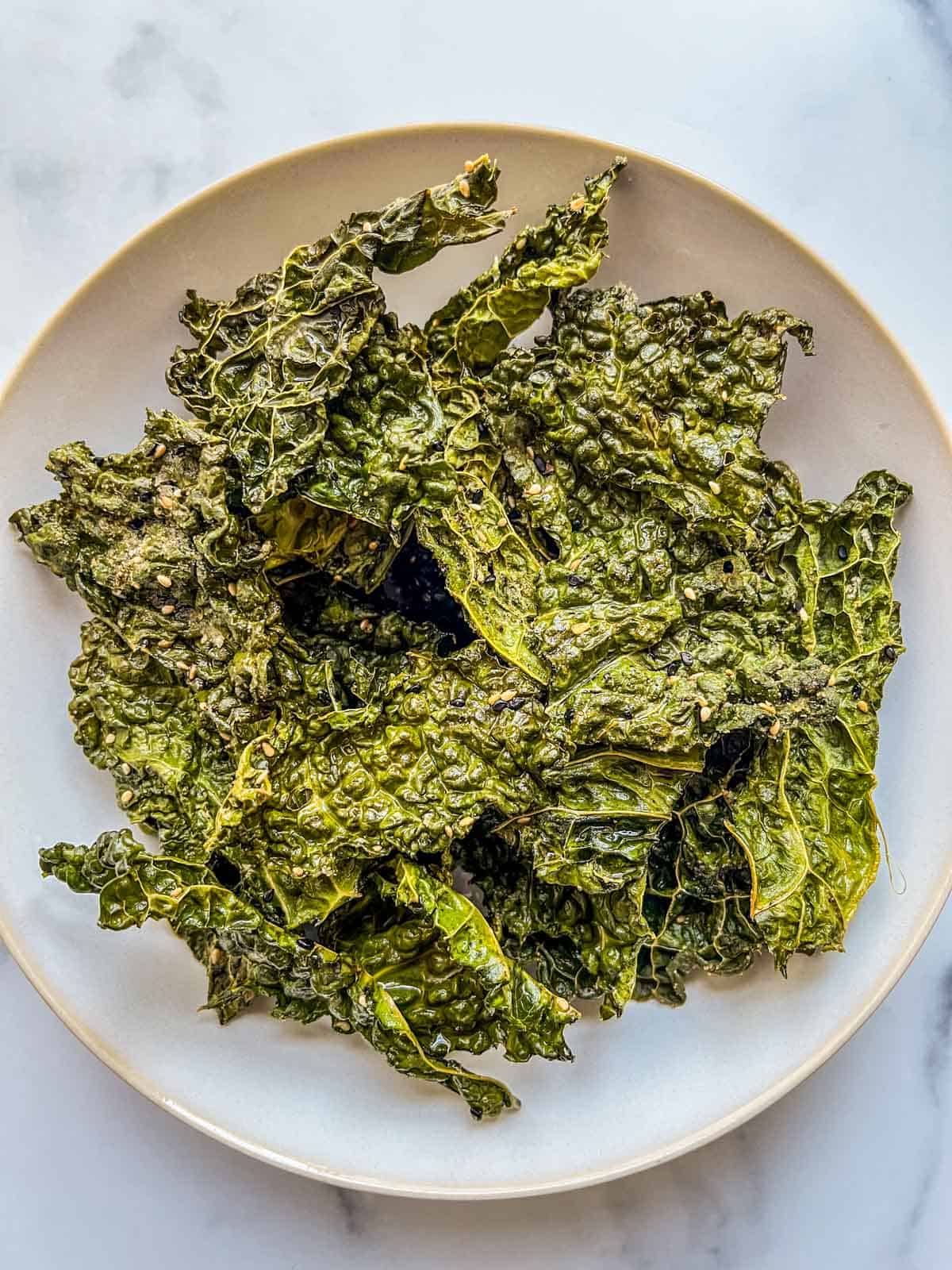 A white serving bowl with crispy savoy cabbage chips.