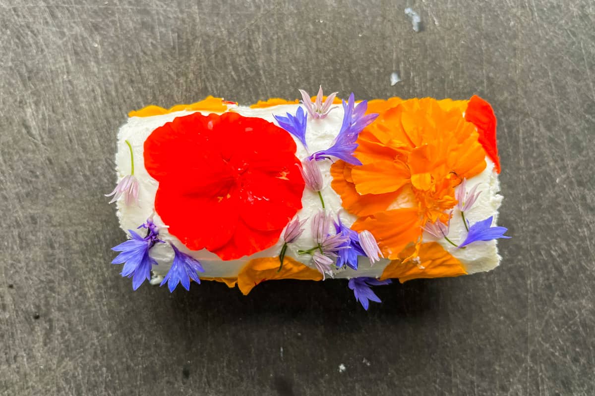 Making edible flower cheese on a cutting board.