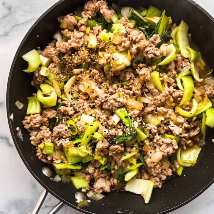 A bok choy and ground pork stir fry in a large skillet.