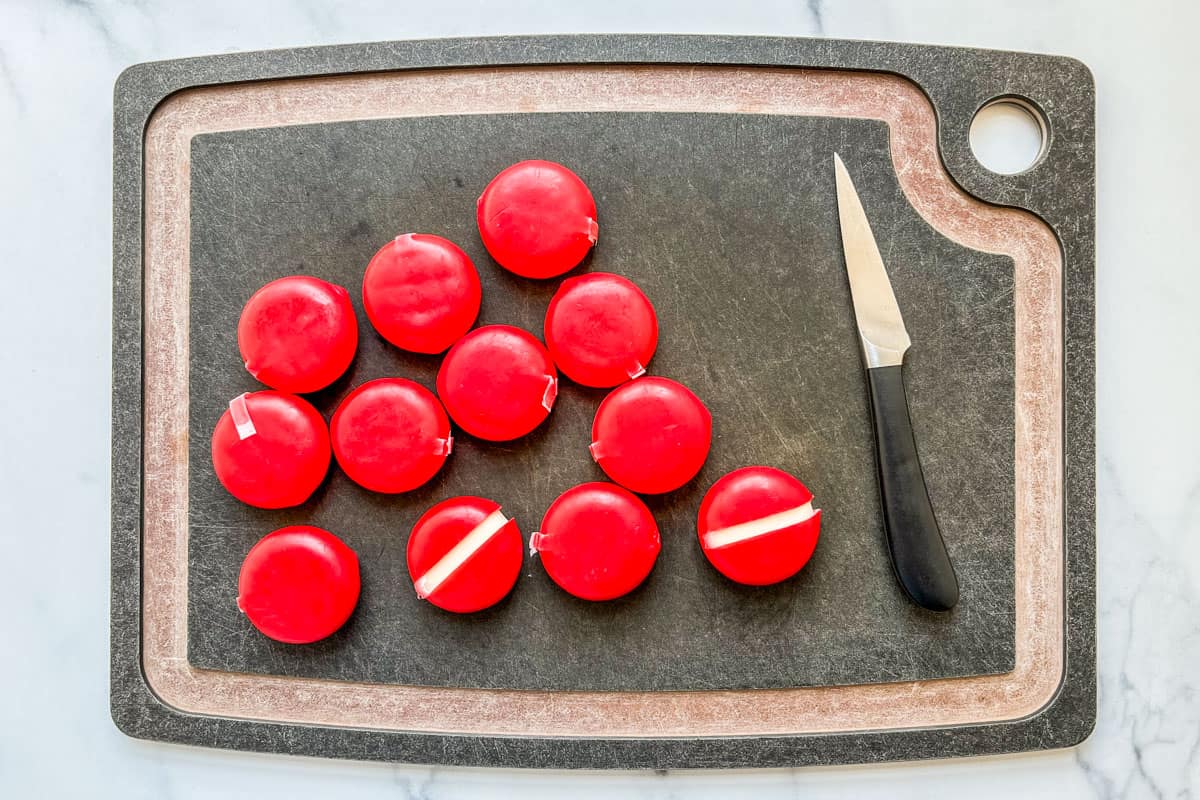 Babybel cheeses on a cutting board with a knife.