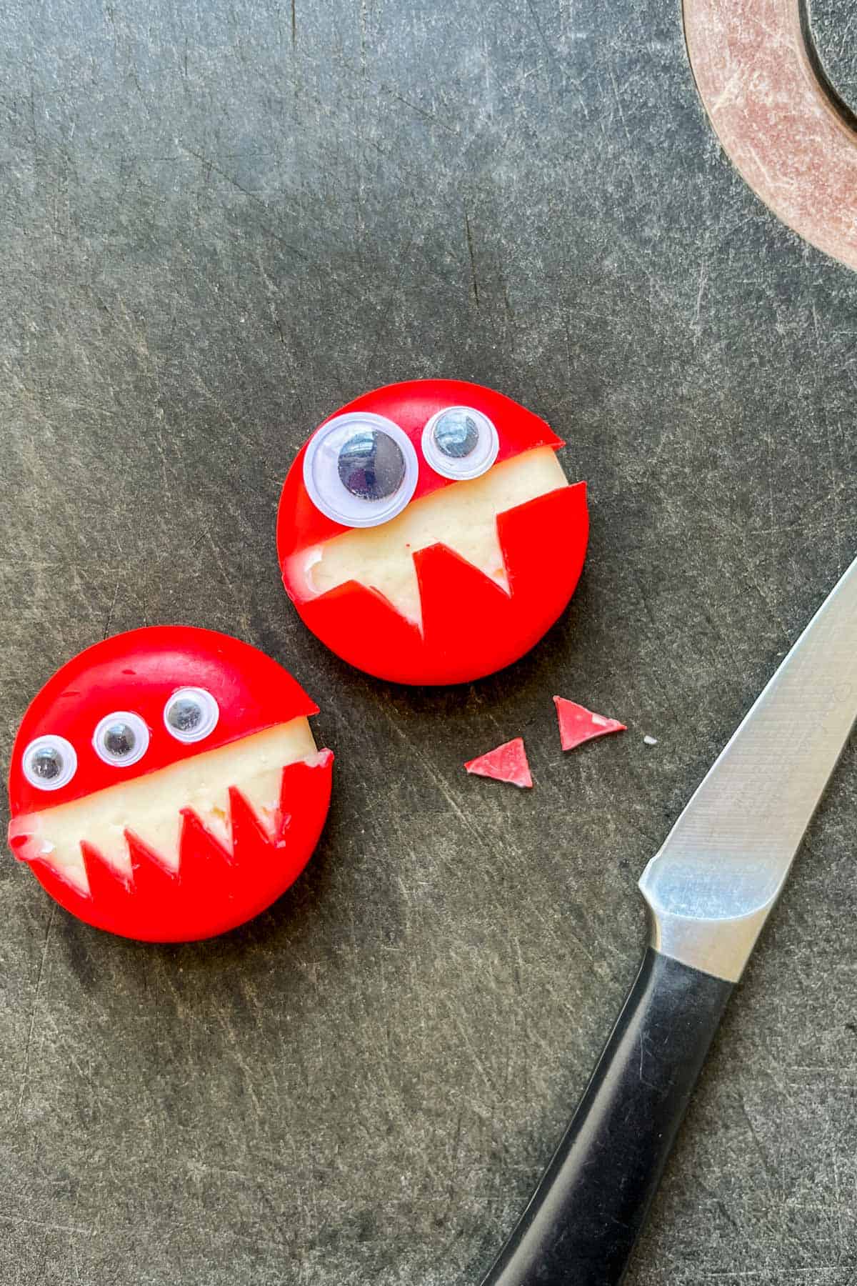 Two babybel cheeses on a cutting board.