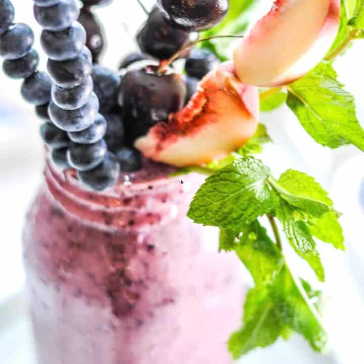 A healthy freakshake with skewers of fruit.