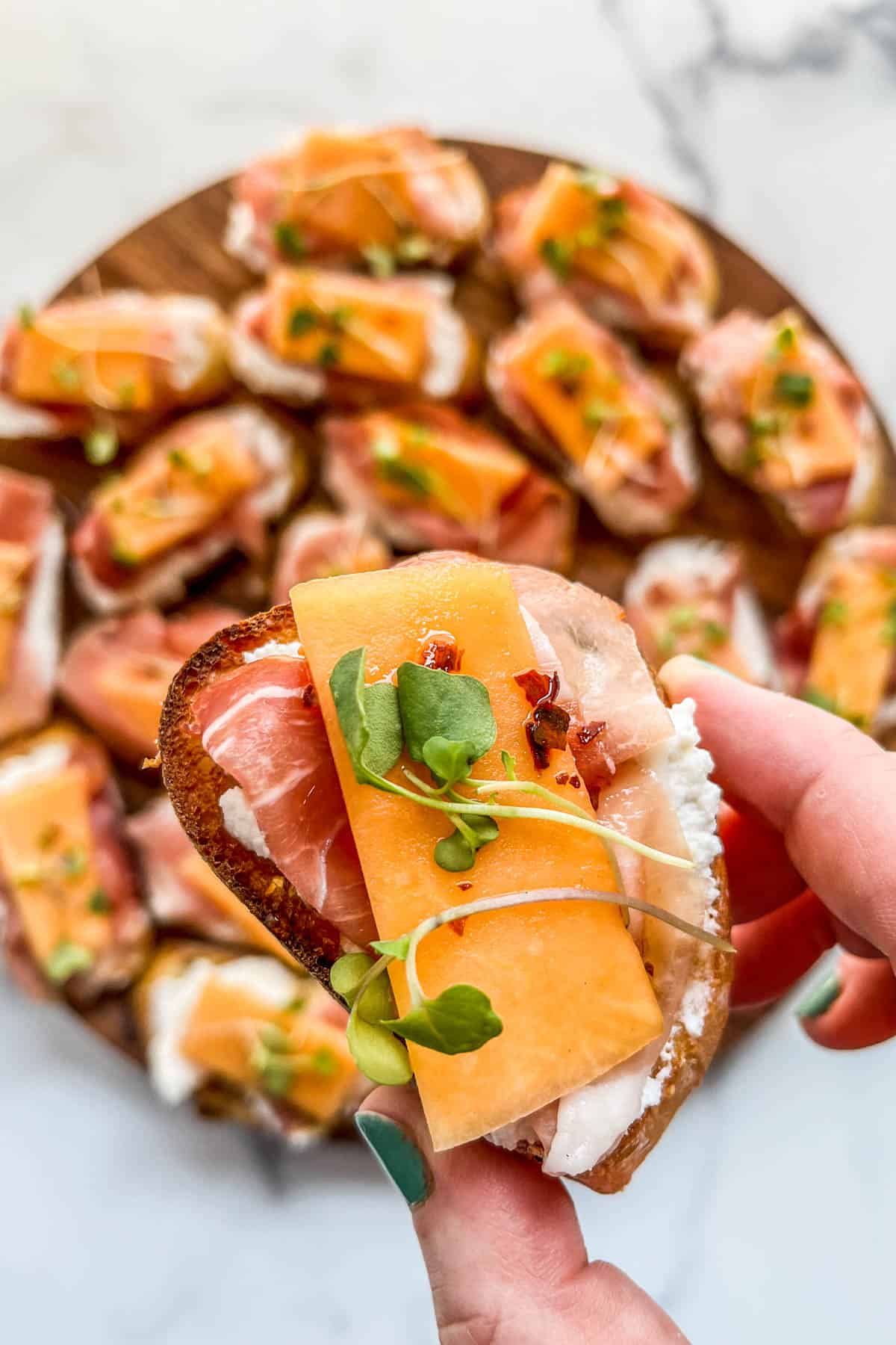 A hand holding a crostini.