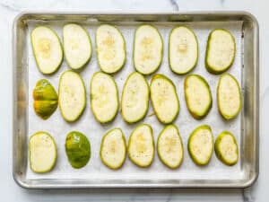Sliced squash on a parchment lined baking sheet.
