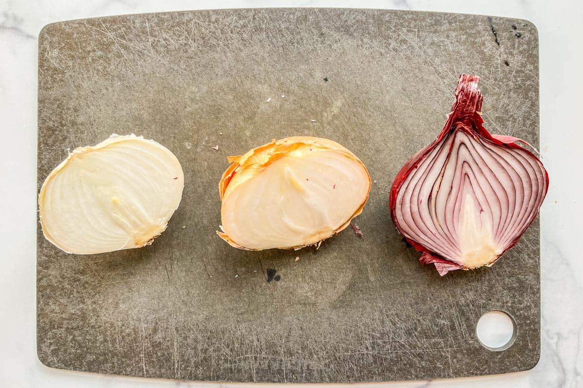 Three onions that have gone bad on a cutting board.