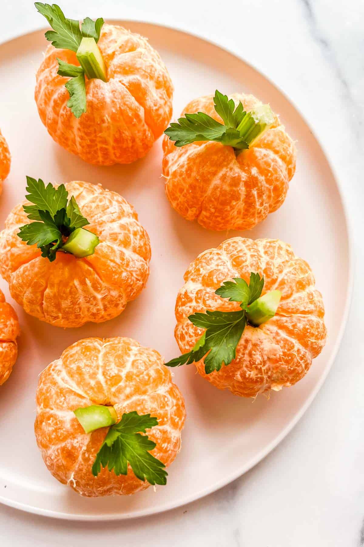 Mandarin orange "pumpkins" on a white plate.