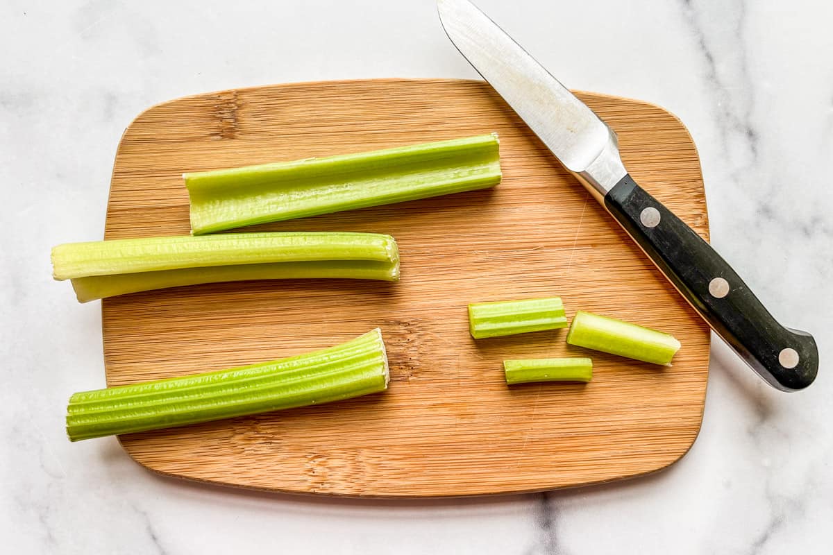 Slicing celery sticks on a cutting board.