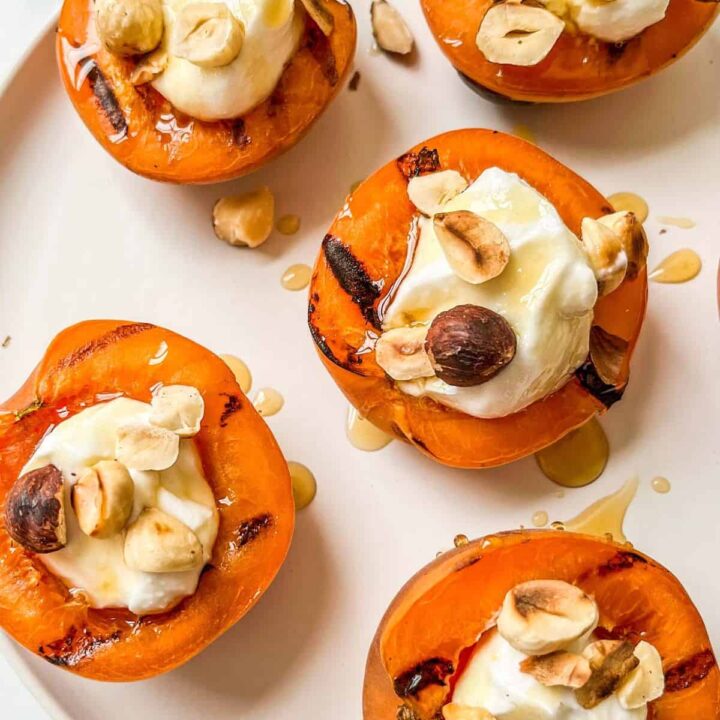 Grilled apricots with yogurt on a white plate.