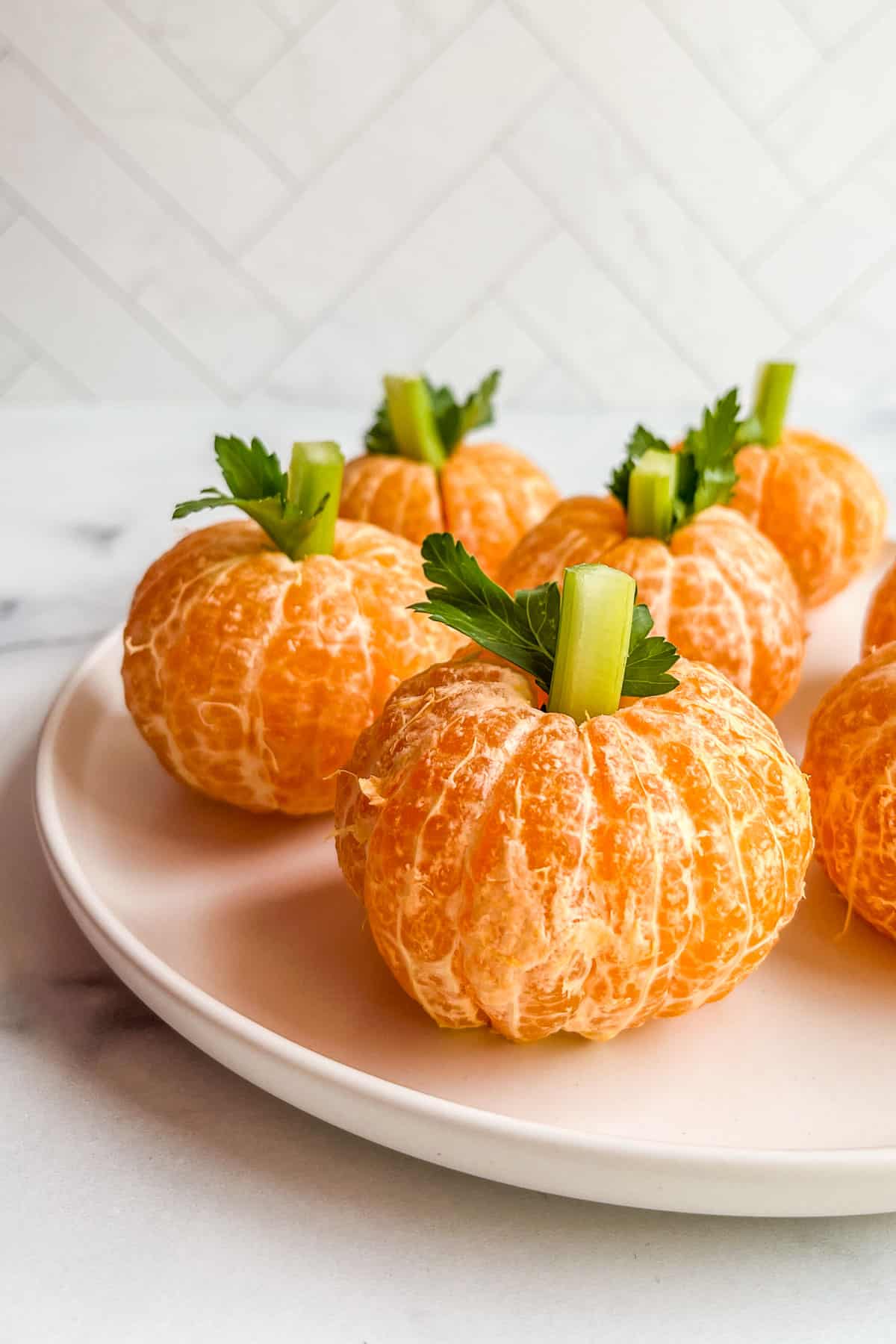 Mandarin orange pumpkins on a white plate.