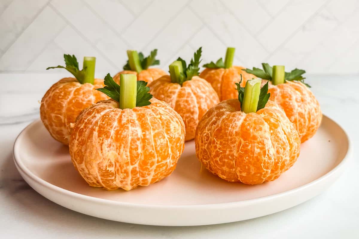 Pumpkin shaped mandarin oranges on a plate.