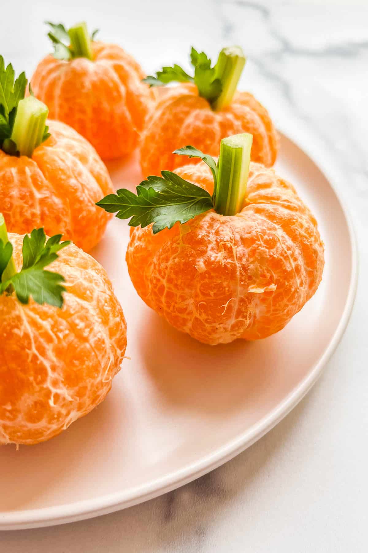 Mandarin orange pumpkins on a white plate.