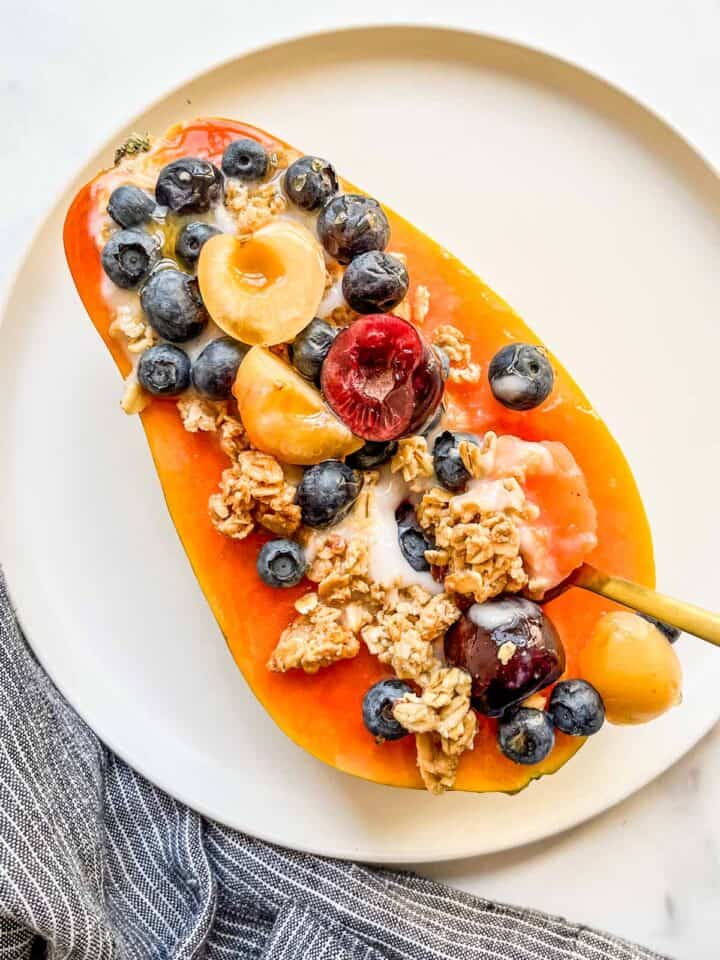A papaya yogurt bowl with granola and fruit.