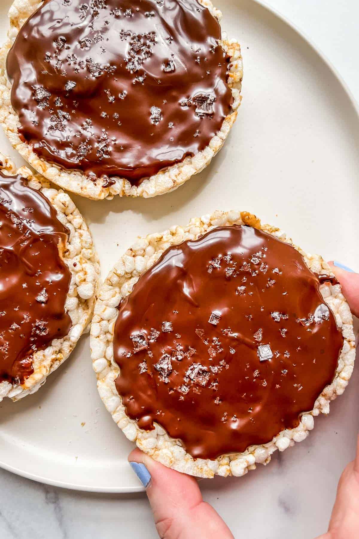 A hand holding a rice cake peanut butter cup.