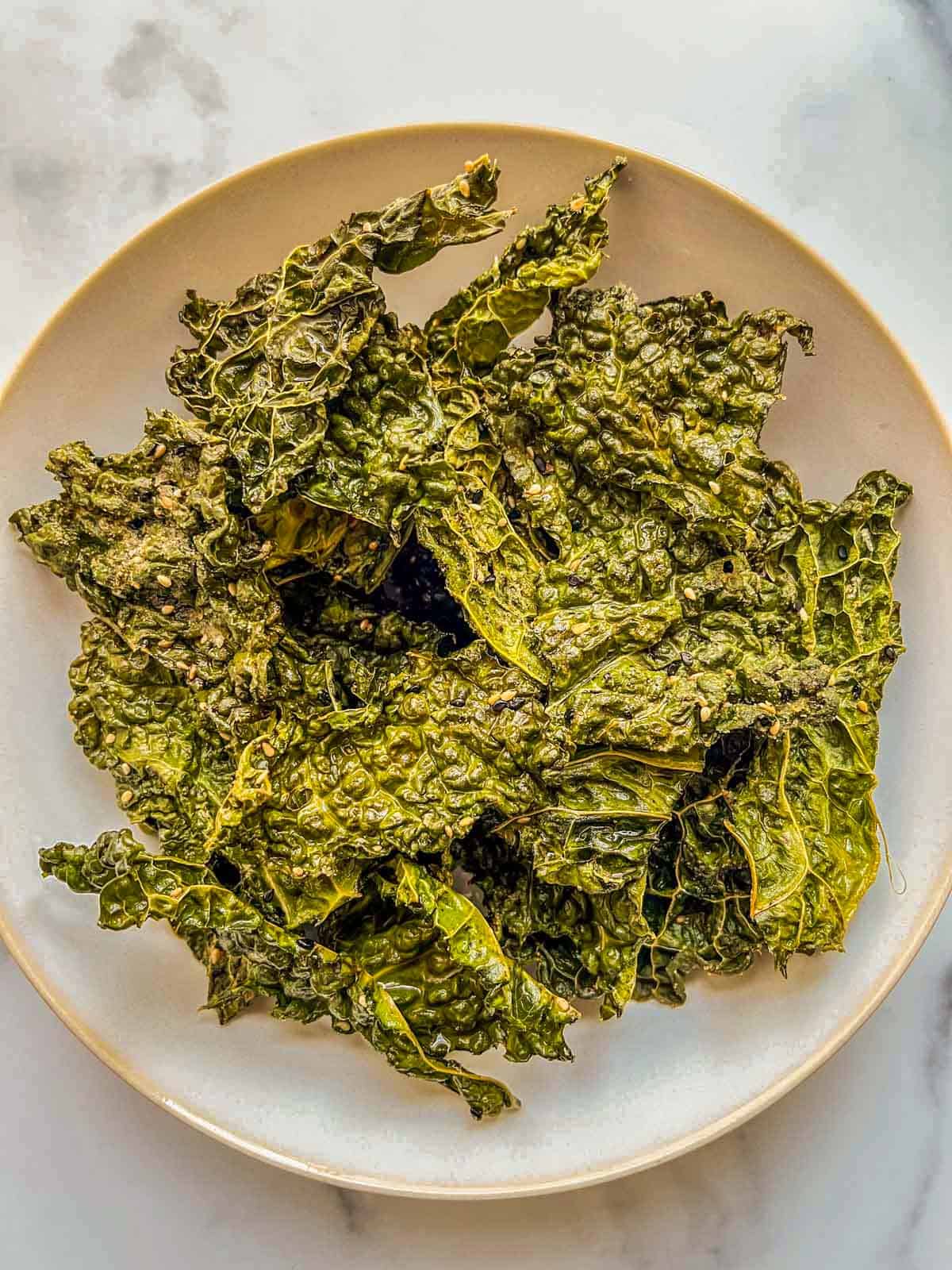 A white serving bowl with crispy savoy cabbage chips.