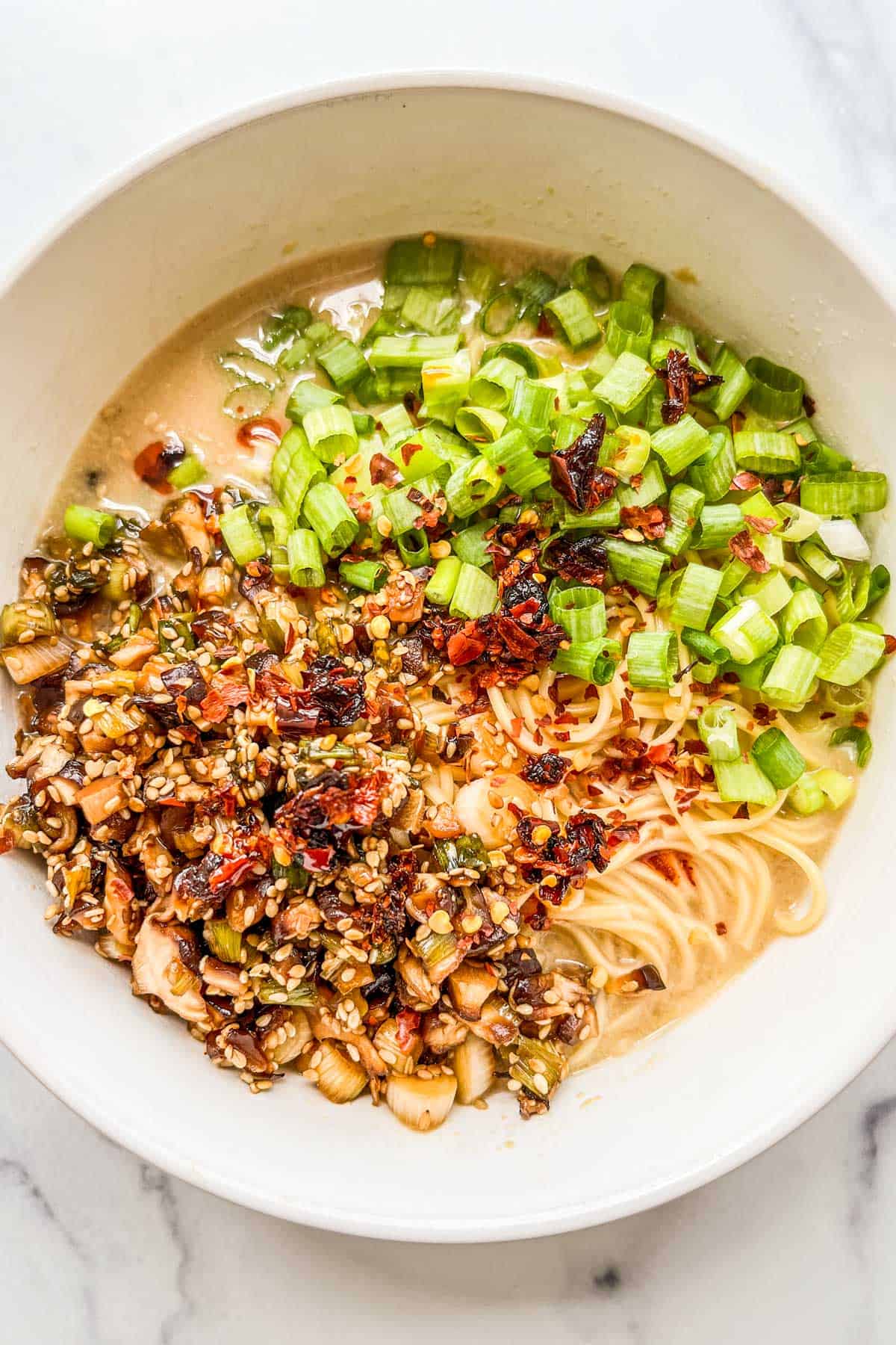 A bowl of tahini miso ramen with mushrooms and scallions.