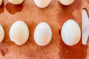 Peeled hard-boiled eggs on a cutting board.