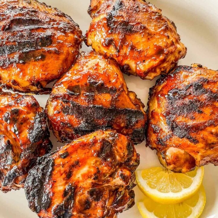 Grilled barbecue chicken thighs on a platter.