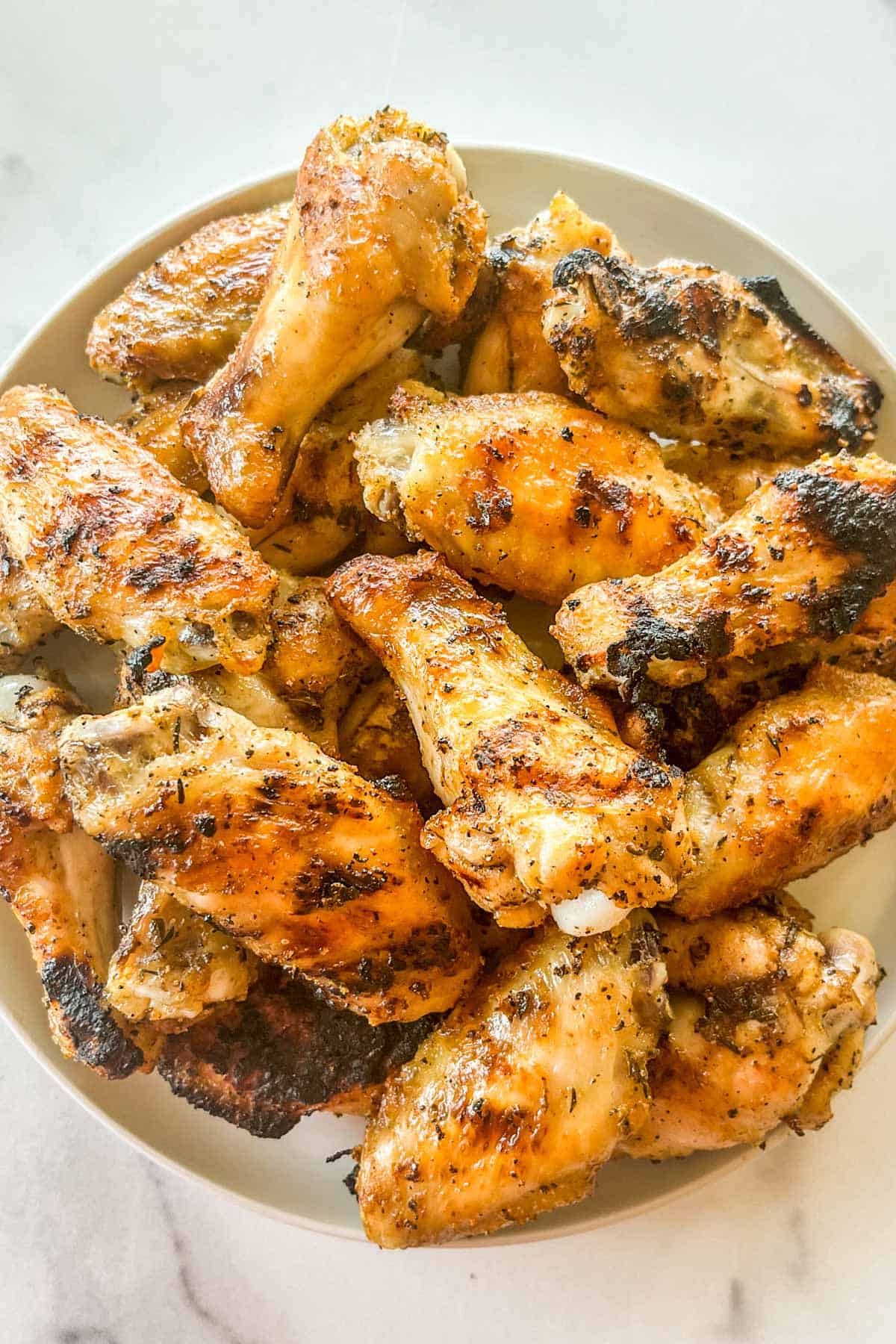 Grilled chicken wings on a white plate.