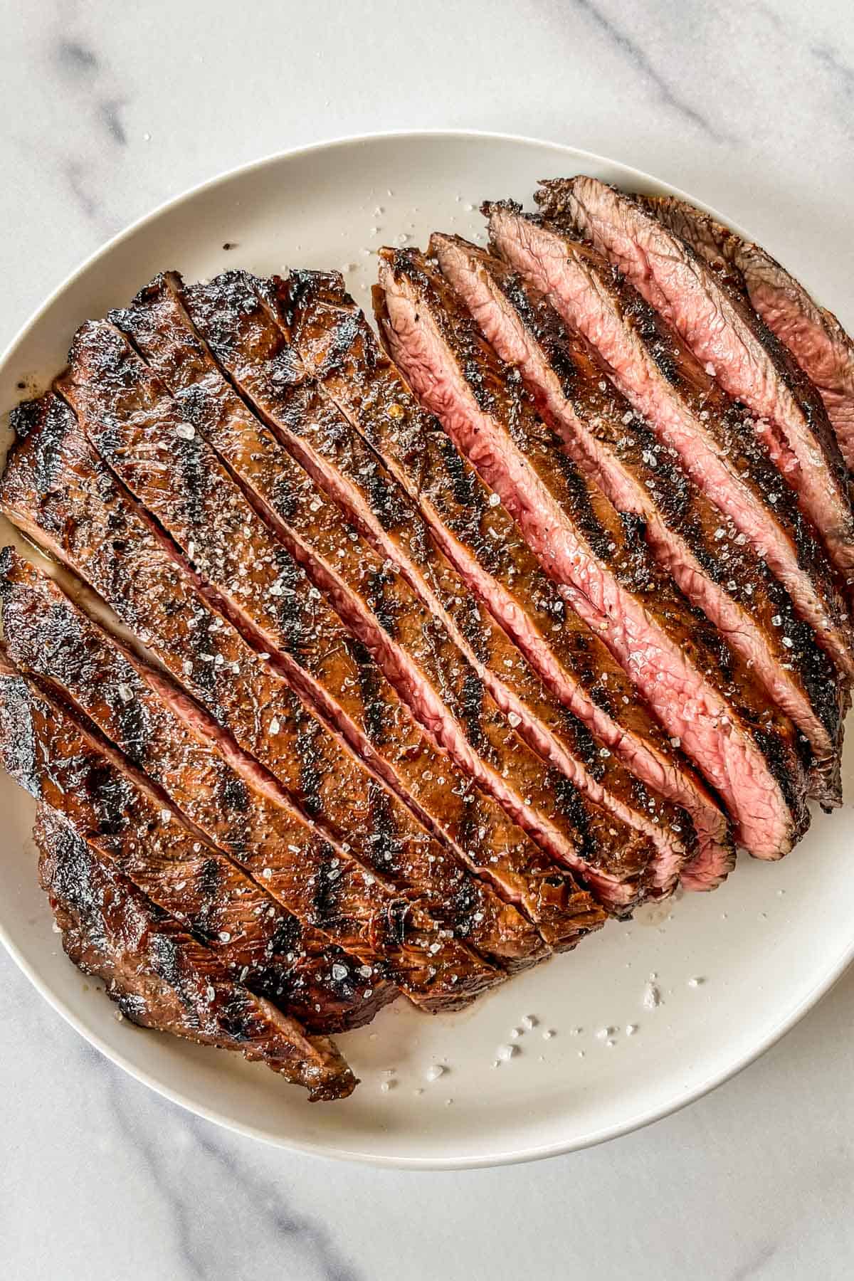 A grilled flank steak on a white plate.
