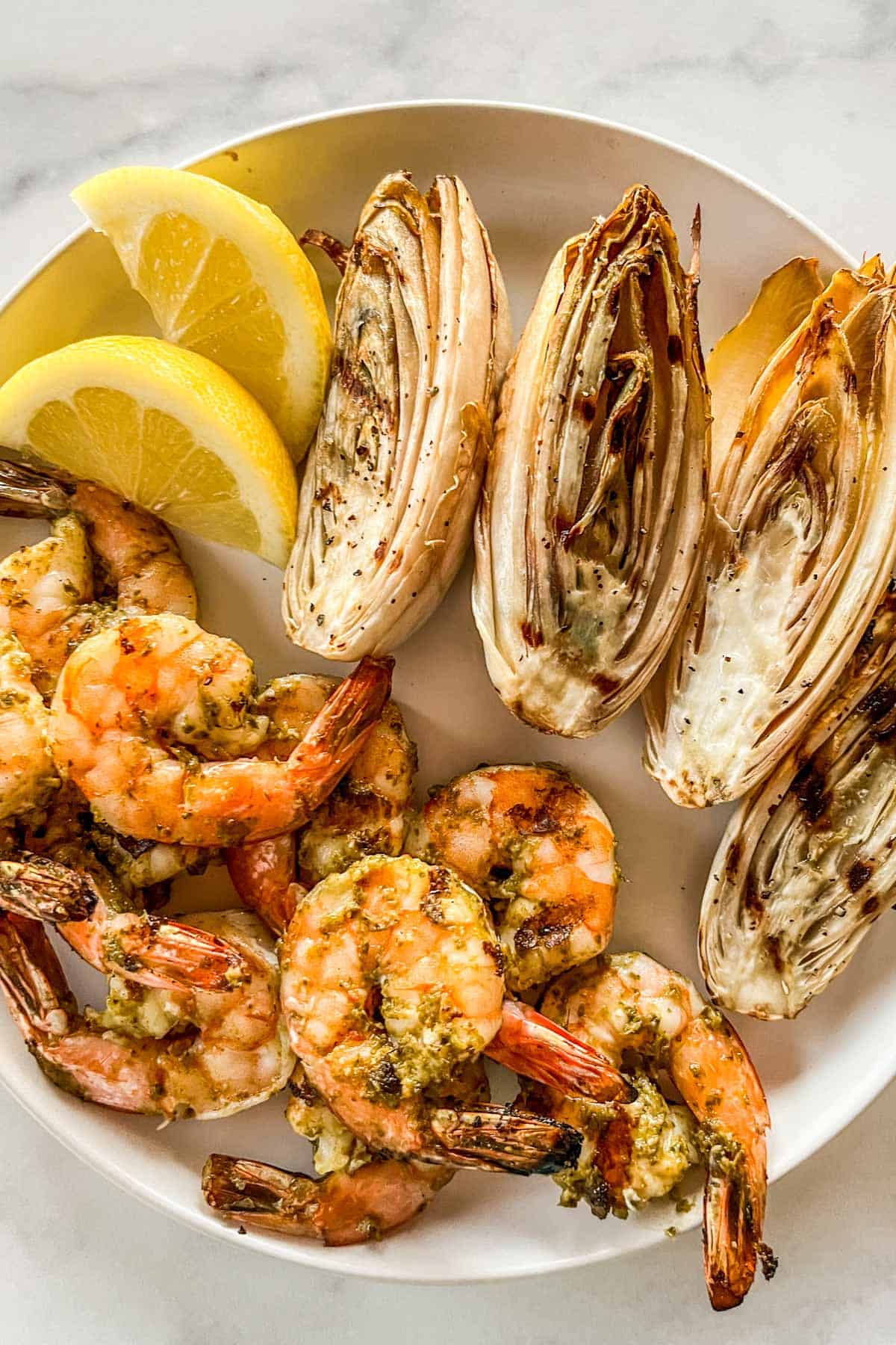 Grilled pesto shrimp and endives on a white plate.