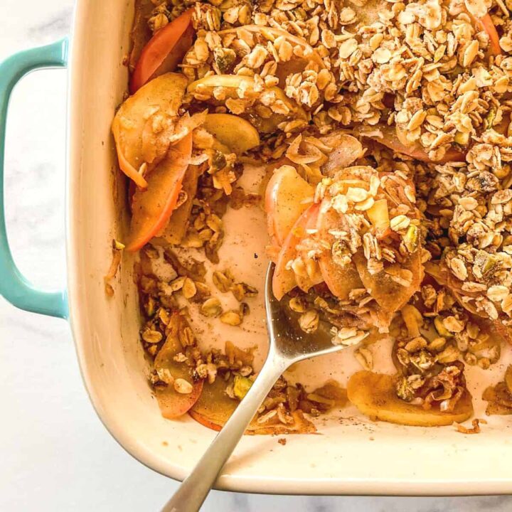 Healthy apple crumble in a baking dish with a spoon.