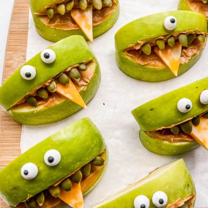 Green apple monsters for Halloween on a cutting board.