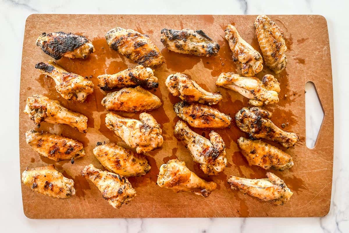 Grilled chicken wings on a cutting board.