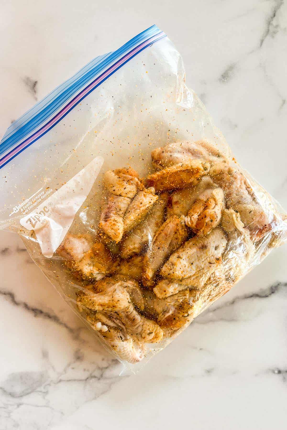 Chicken wings marinating in spices in a ziploc bag.