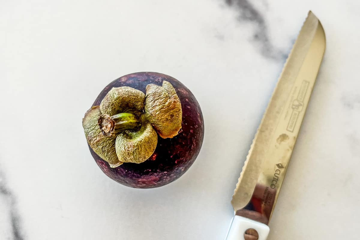 A mangosteen with a serrated knife.