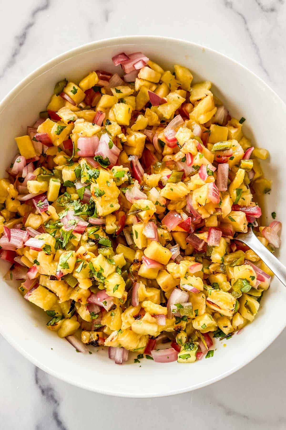 Grilled pineapple salsa in a bowl with a spoon.