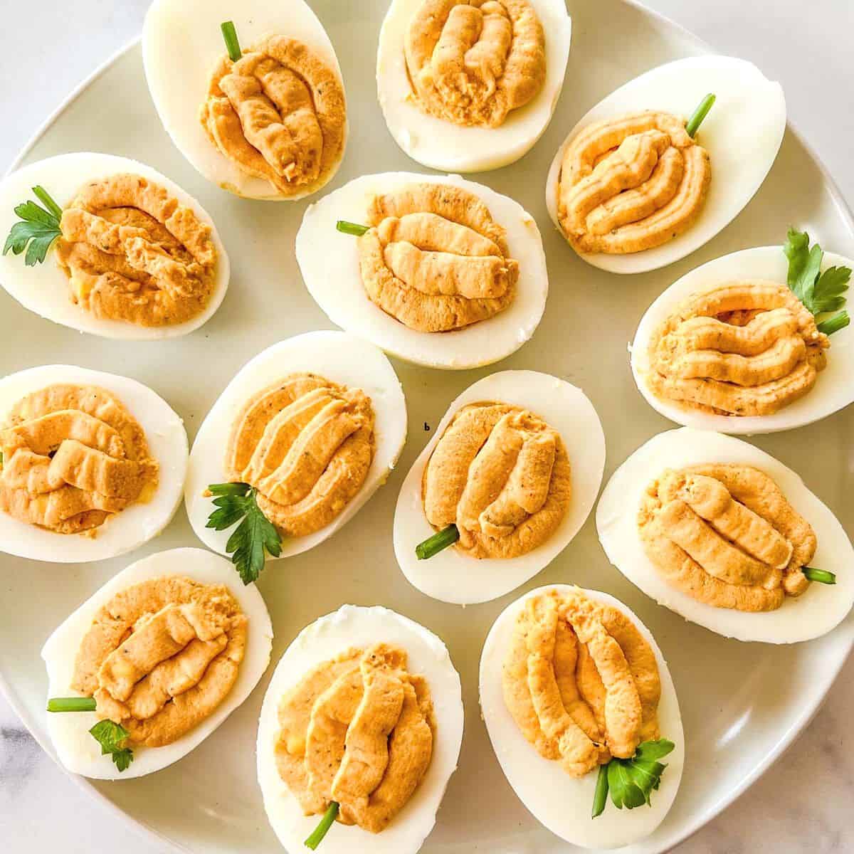 Pumpkin deviled eggs on a plate.
