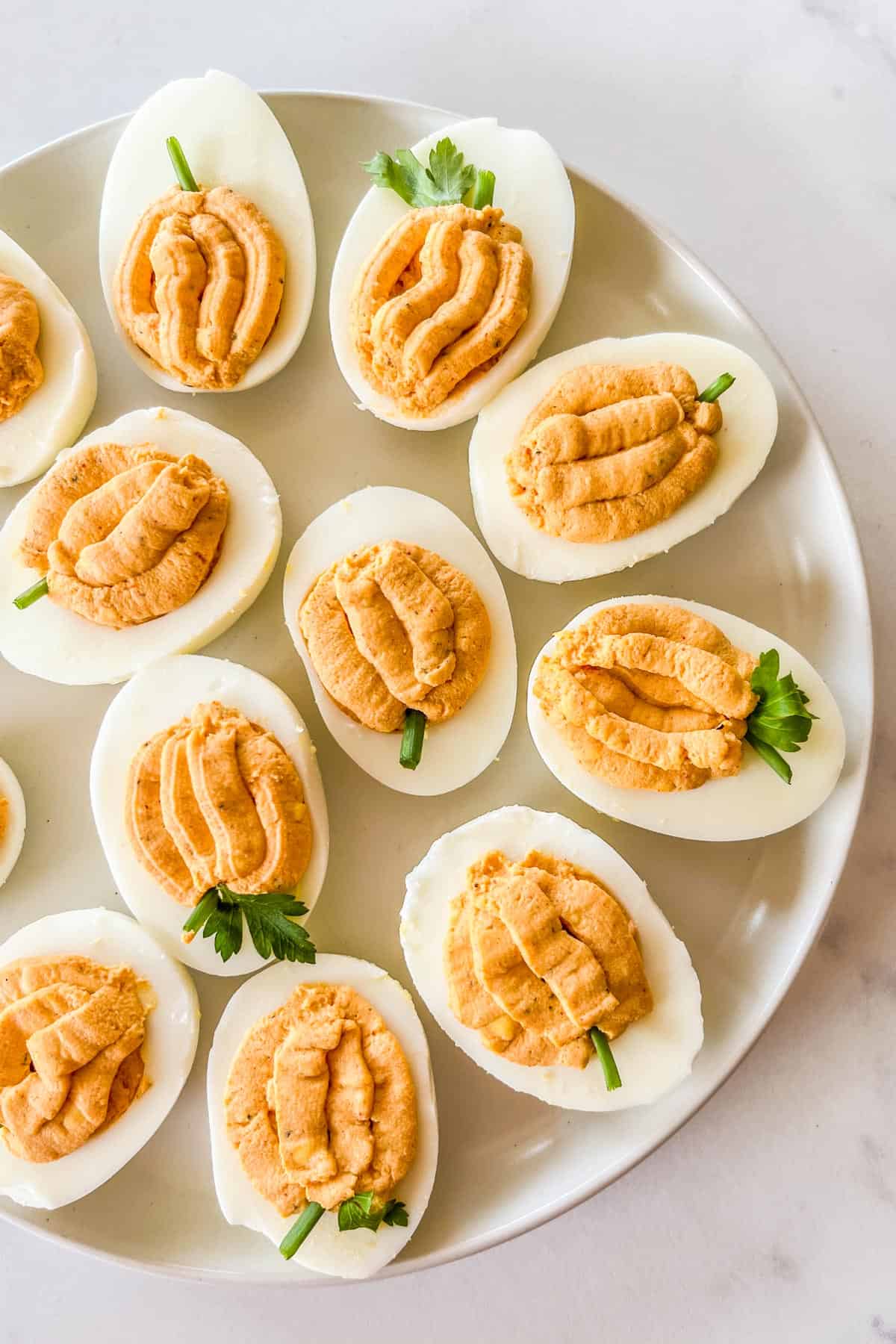 Pumpkin deviled eggs on a plate.