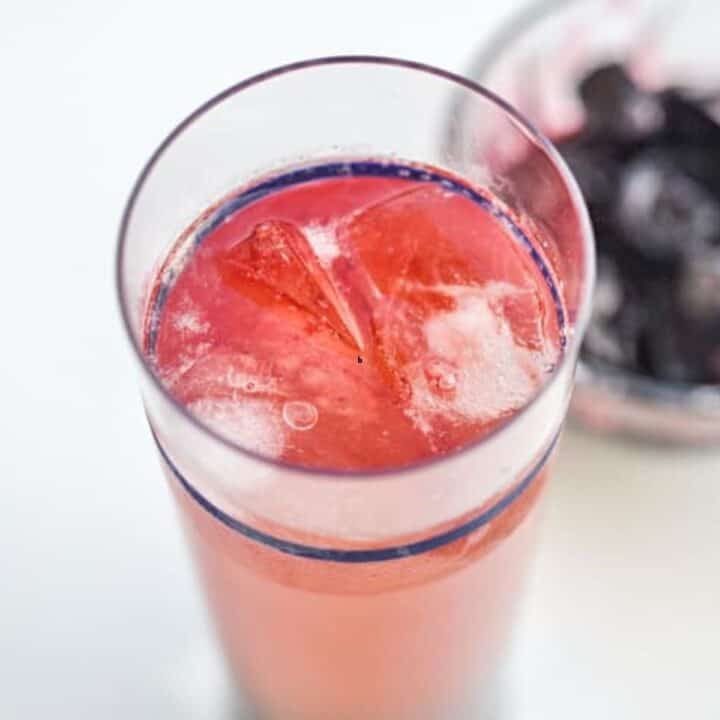 A sunset whiskey sour drink in a tall glass.