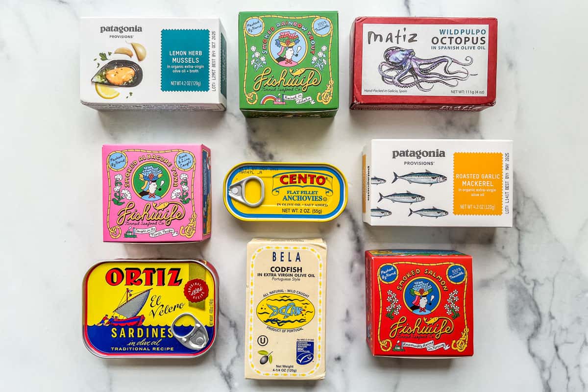 Several types of canned fish on a marble background.