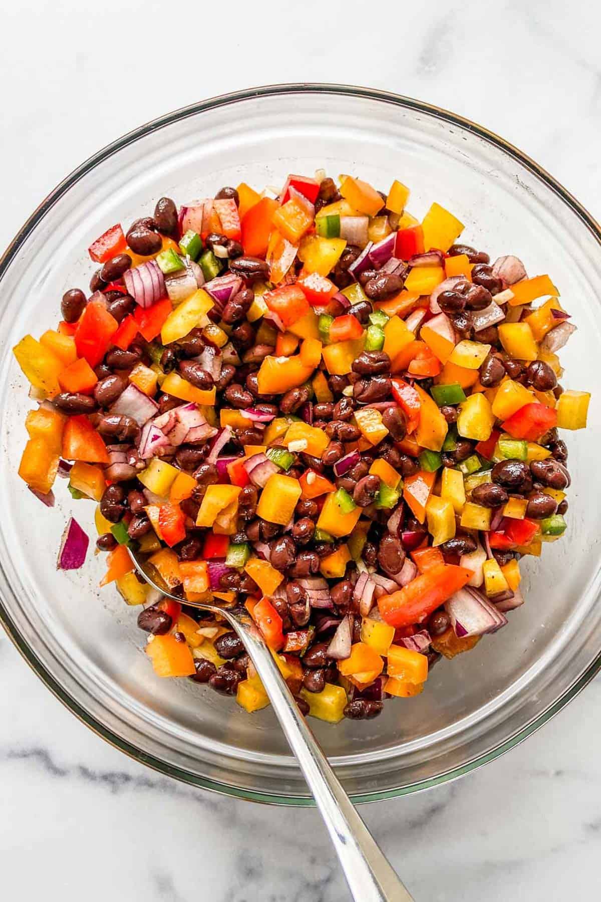 A black bean salad with bell peppers in a glass bowl.