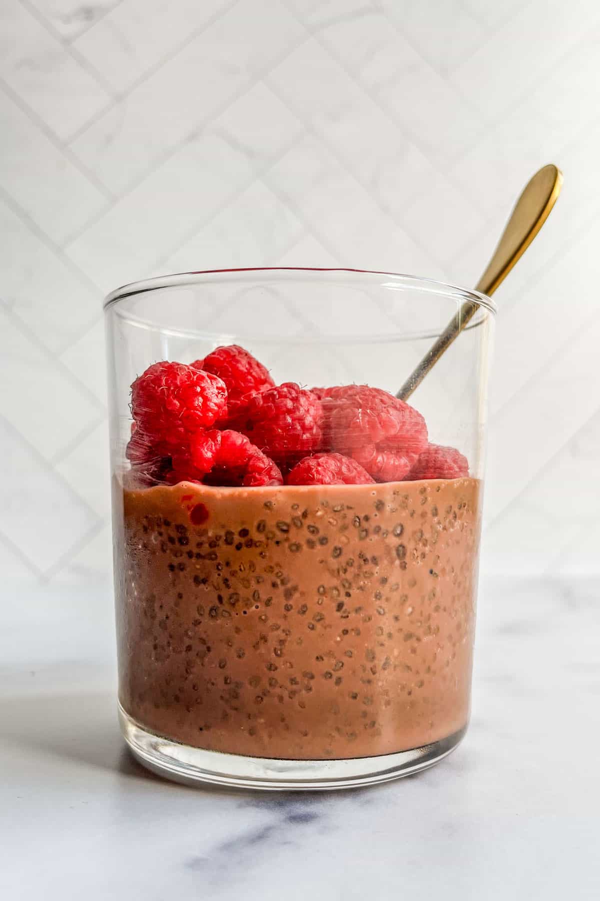 Chocolate chia seed pudding topped with raspberries in a glass.