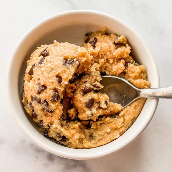 Healthy edible cookie dough with chocolate chips in a white bowl with a spoon.