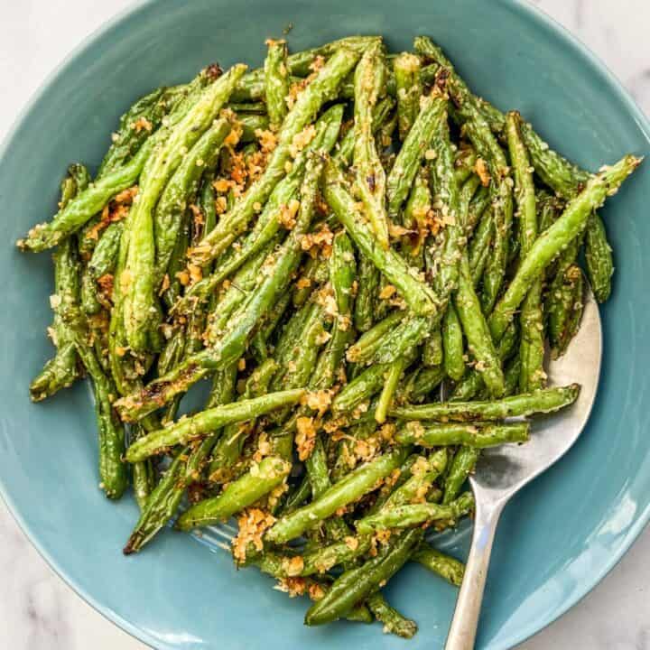 Parmesan green beans in a large blue serving bowl.