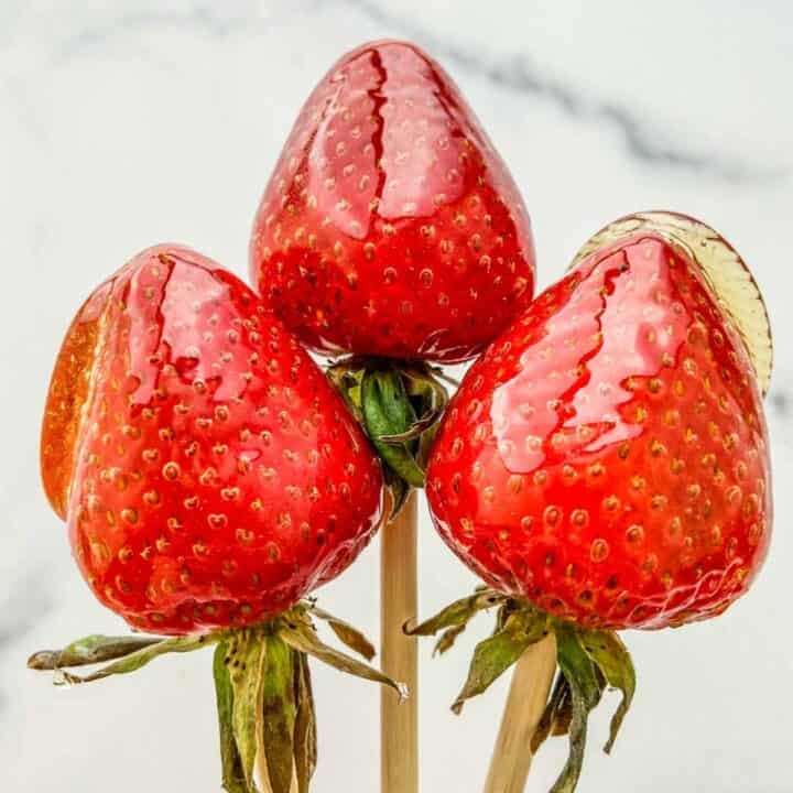 Three tanghulu strawberries on skewers.