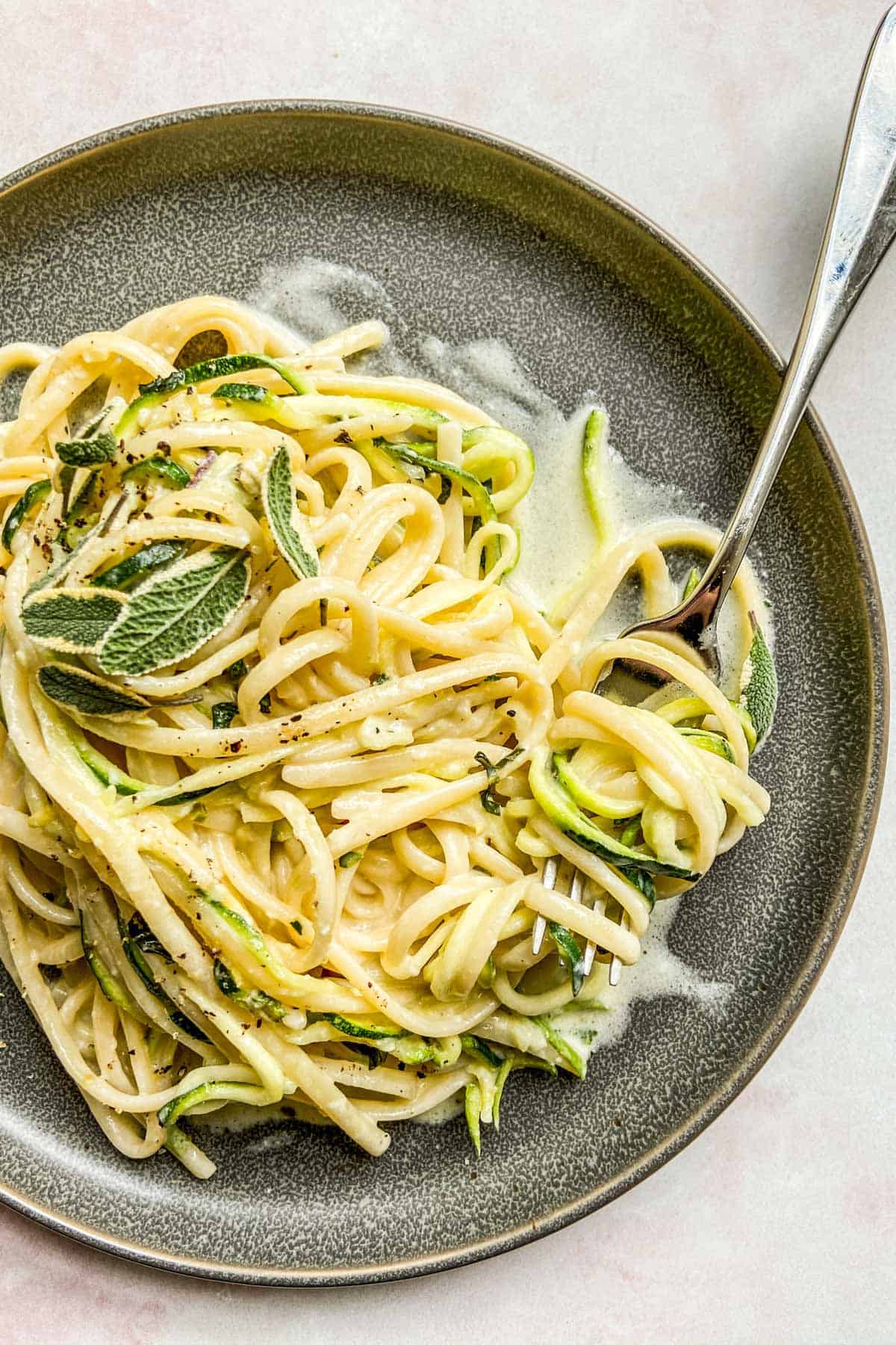 A fork scooping up some zucchini pasta.