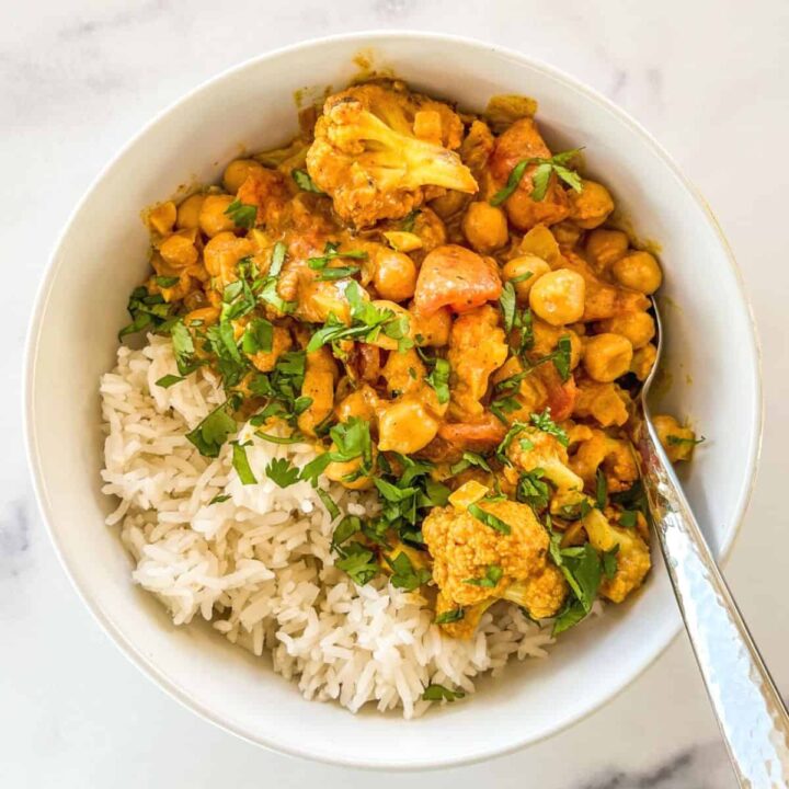 A white bowl with rice and cauliflower chickpea curry.
