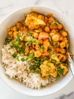 Cauliflower chickpea curry with rice in a white bowl.