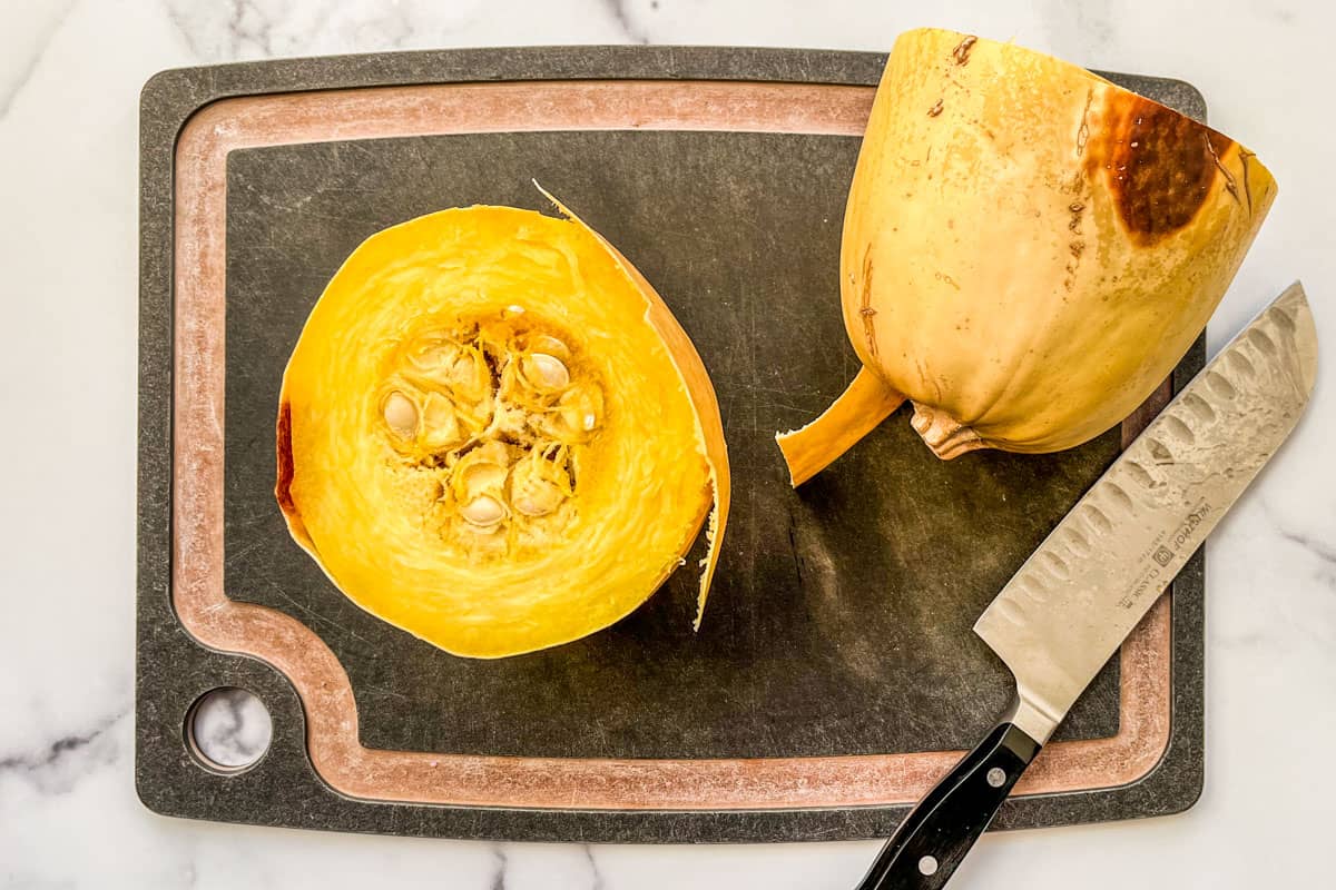 A roasted spaghetti squash, cut in half on a cutting board.