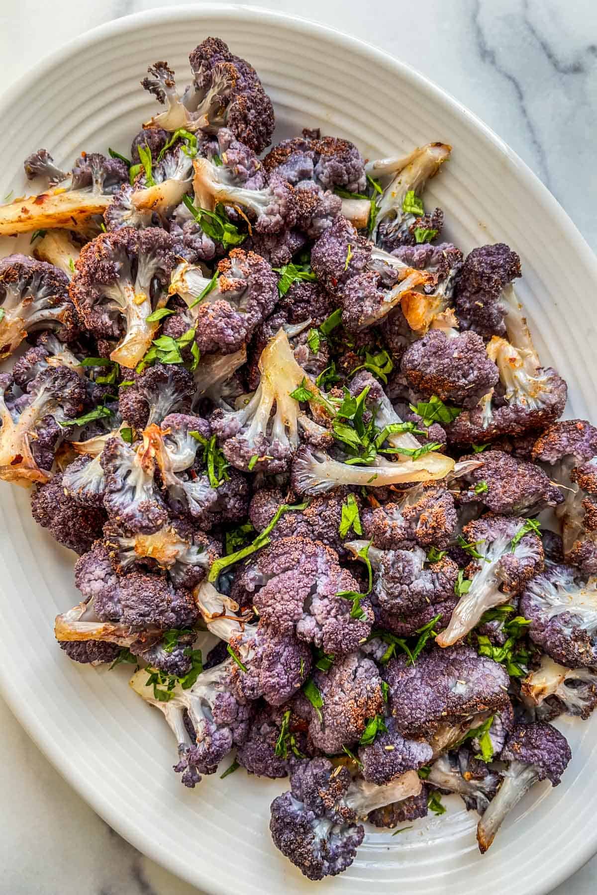 Roasted purple cauliflower on a large serving platter.