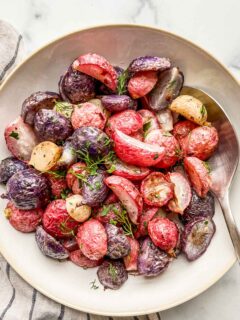 Roasted radishes topped with fresh herbs in a serving bowl.