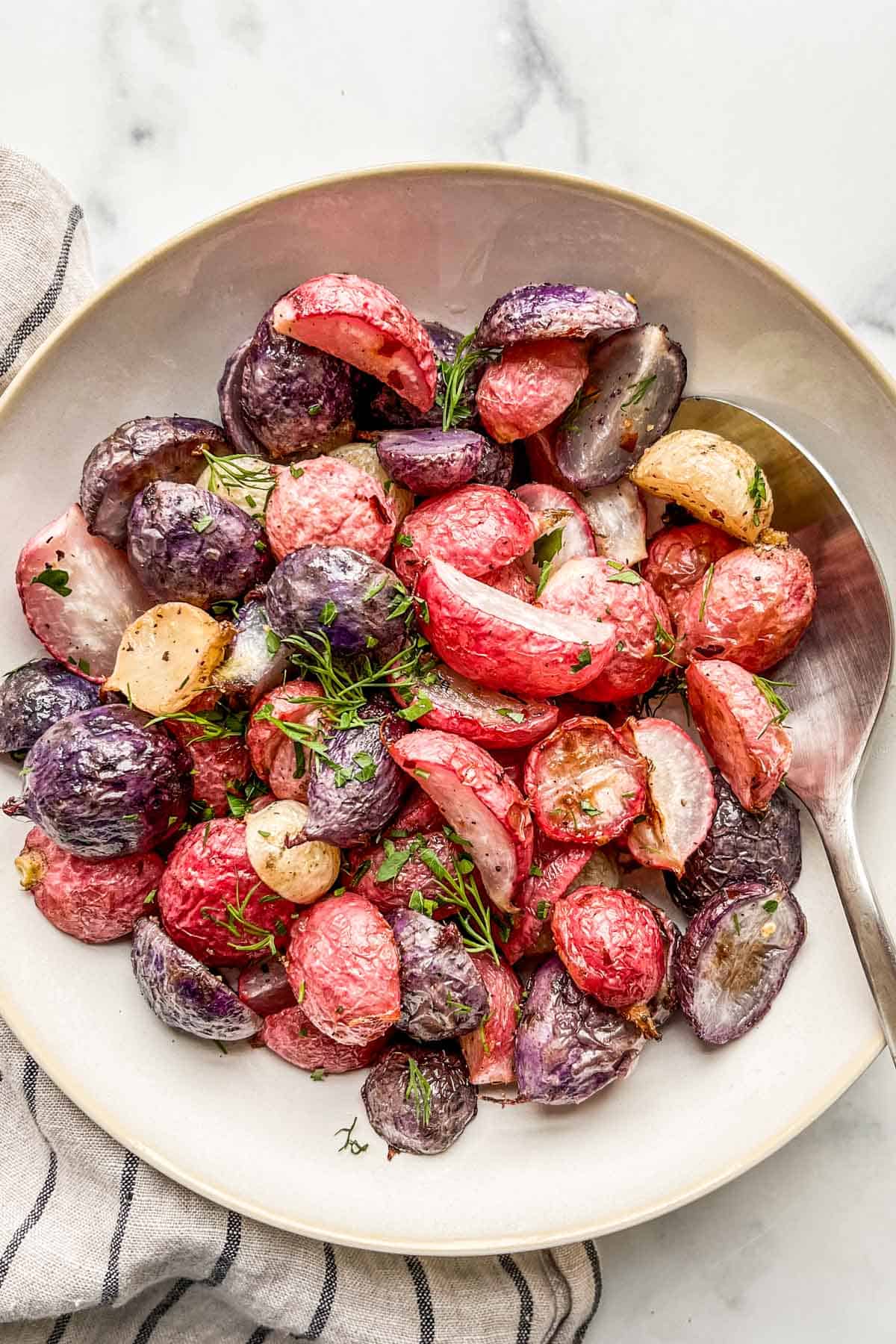 Roasted radishes topped with fresh herbs in a serving bowl.