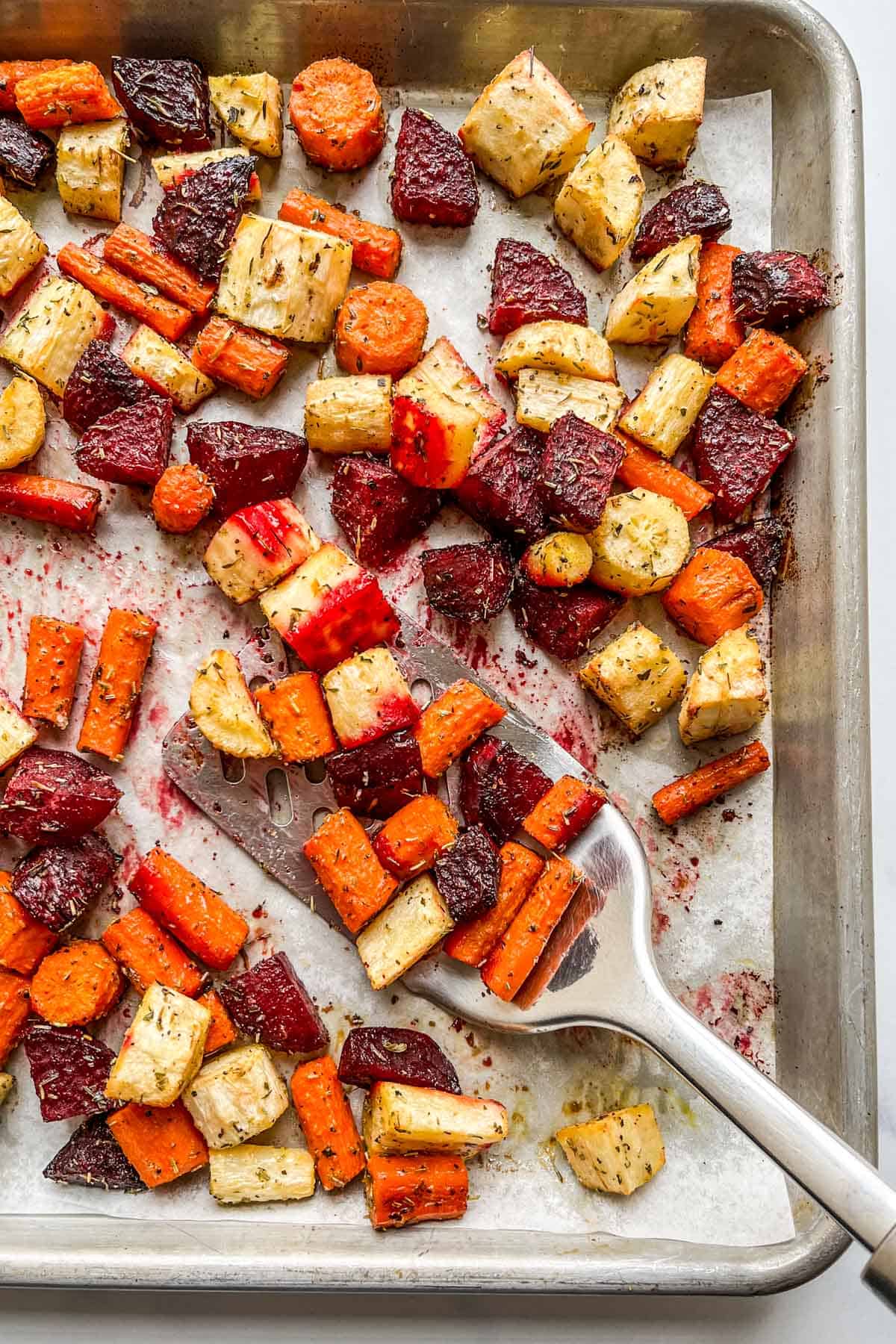 Roasted root vegetables on a parchment lined baking sheet.